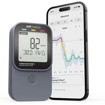 Moniteur Airthings 325 Corentium Home 2 : l'appareil blanc debout à droite, son petit écran allumé, présenté à côté de sa boîte
